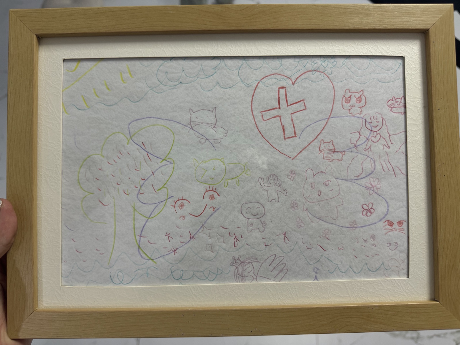 Coloured line drawing filling the page: cats, small figures, a tree, flowers, a large red heart with a cross inside, and rows of waves along the top and bottom.