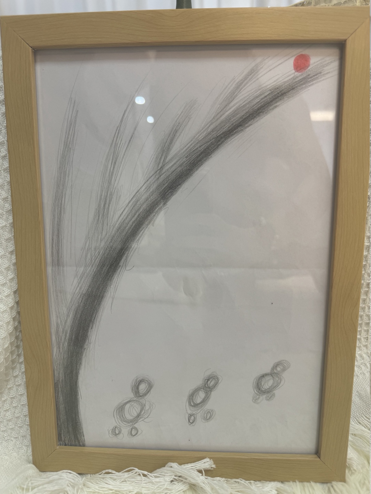 Graphite drawing: a wide sweeping arc rising across the page, a small red dot at its upper end, and three small circular figures below.