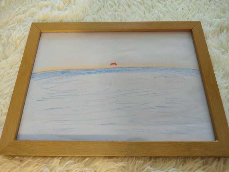 Coloured-pencil drawing of a small red sun on the horizon above a broad blue sea, framed in light wood.