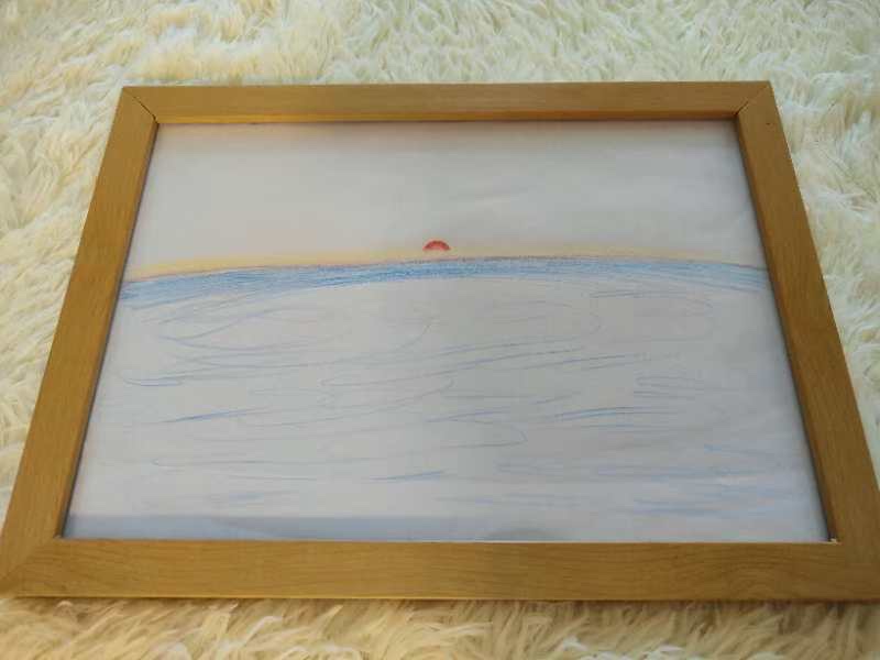 Coloured-pencil drawing of a small red sun on the horizon above a broad blue sea, framed in light wood.